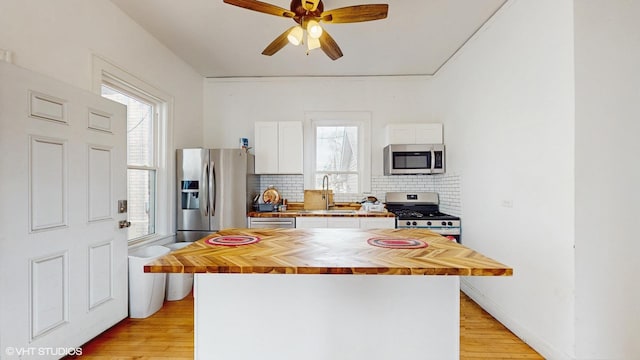 kitchen with white cabinetry, a sink, wood counters, and appliances with stainless steel finishes