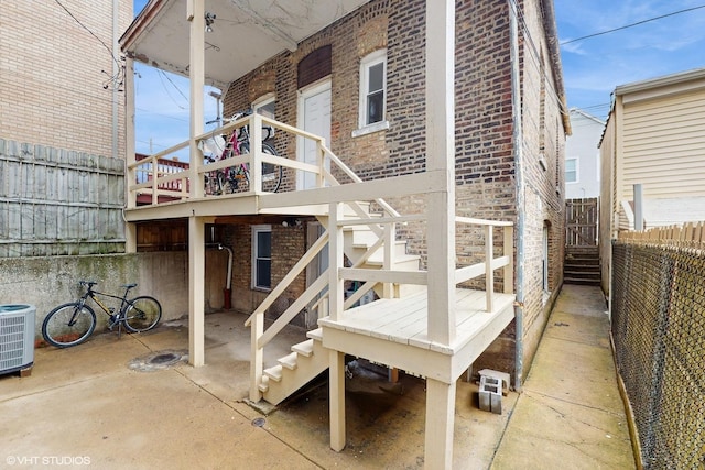 exterior space with stairway, brick siding, fence, and central AC unit
