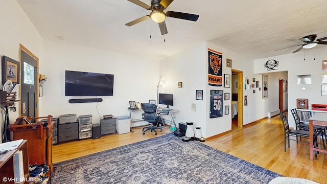 living room featuring wood finished floors, a baseboard heating unit, and a ceiling fan