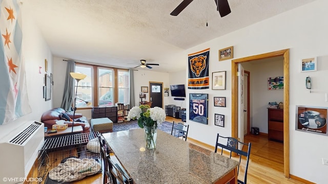dining room with a ceiling fan, baseboards, light wood finished floors, and a textured ceiling