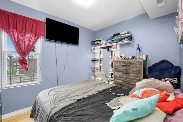 bedroom with wood finished floors, baseboards, and visible vents
