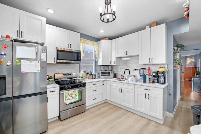 kitchen with white cabinetry, light countertops, tasteful backsplash, light wood finished floors, and appliances with stainless steel finishes