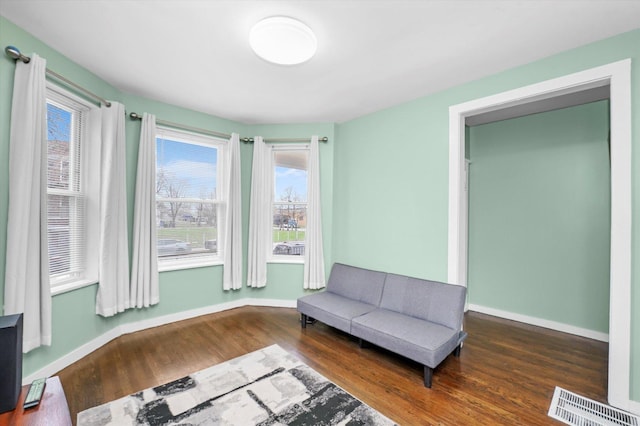 living area with wood finished floors, baseboards, and visible vents
