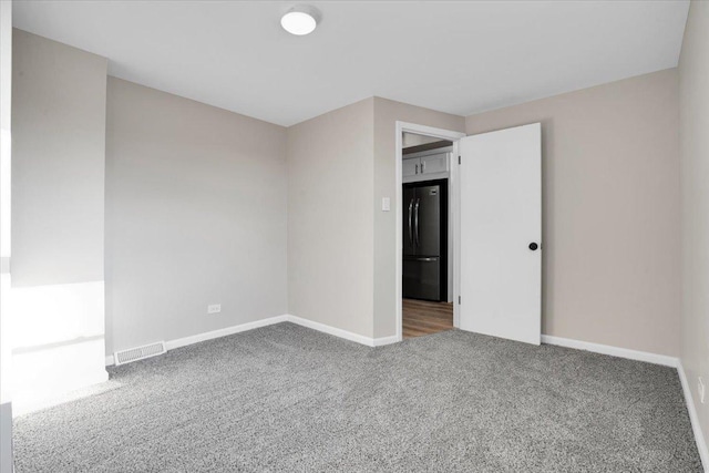 spare room with carpet floors, baseboards, and visible vents
