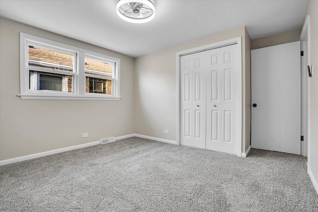 unfurnished bedroom featuring baseboards, carpet, a closet, and visible vents