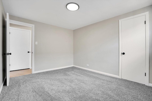 spare room with baseboards and carpet floors