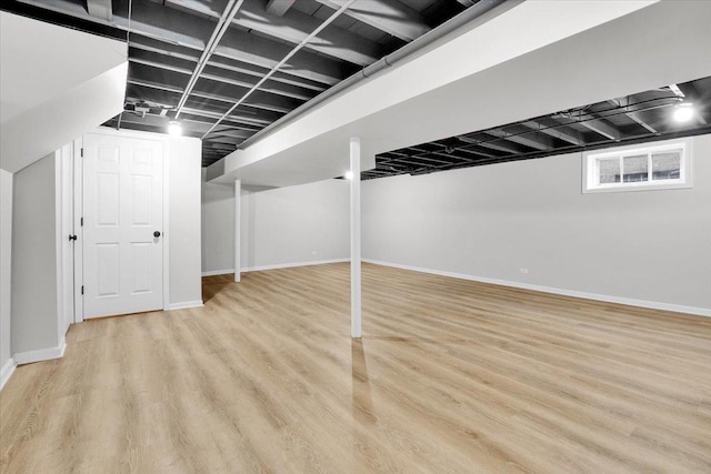 basement with baseboards and light wood-style floors