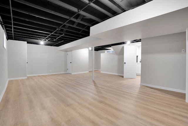 finished basement featuring baseboards and light wood-type flooring