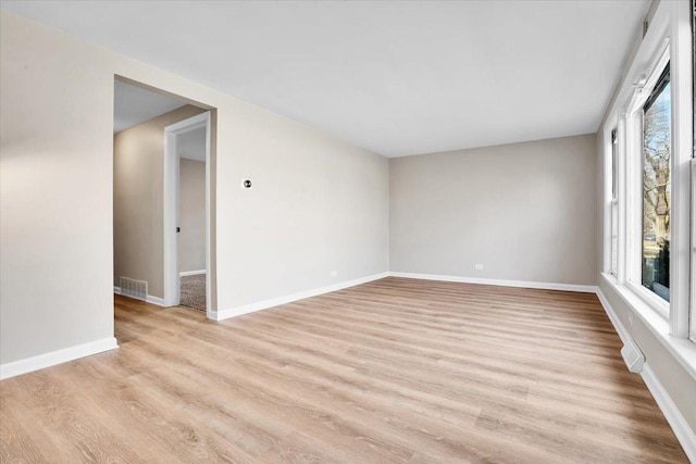 spare room featuring baseboards, light wood finished floors, and visible vents
