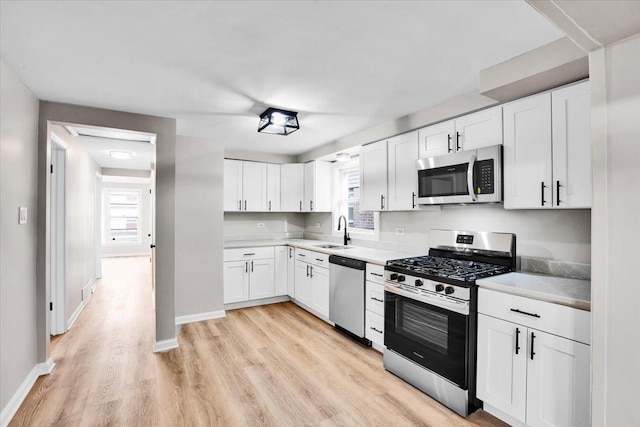kitchen with a sink, a wealth of natural light, appliances with stainless steel finishes, and white cabinetry