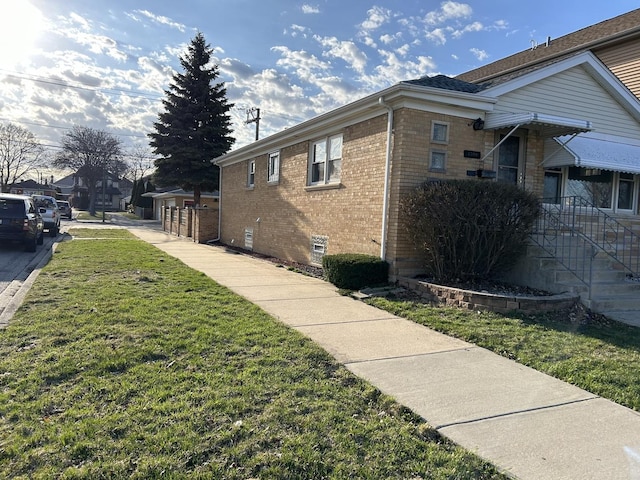 view of property exterior with a lawn, brick siding, and crawl space