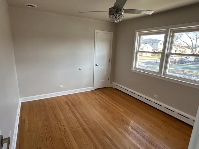 empty room with baseboards, a ceiling fan, baseboard heating, and light wood finished floors