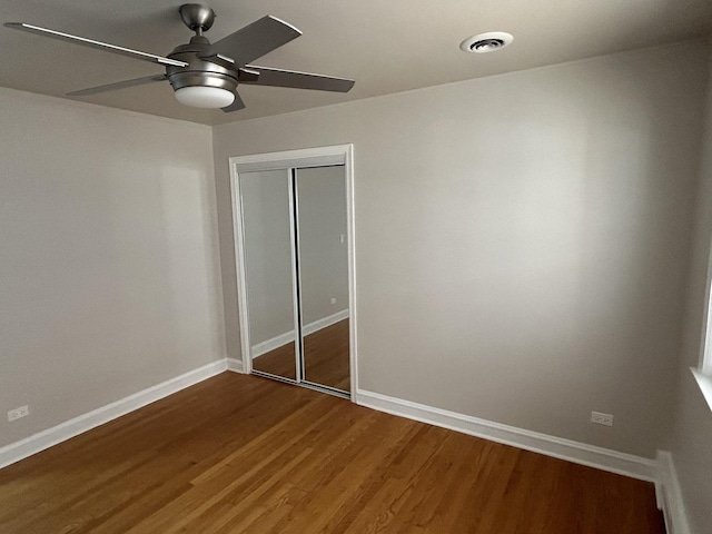 unfurnished bedroom featuring a closet, baseboards, wood finished floors, and a ceiling fan