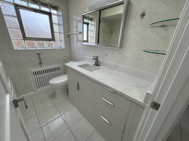 full bath featuring toilet, vanity, radiator heating unit, tile patterned flooring, and tile walls