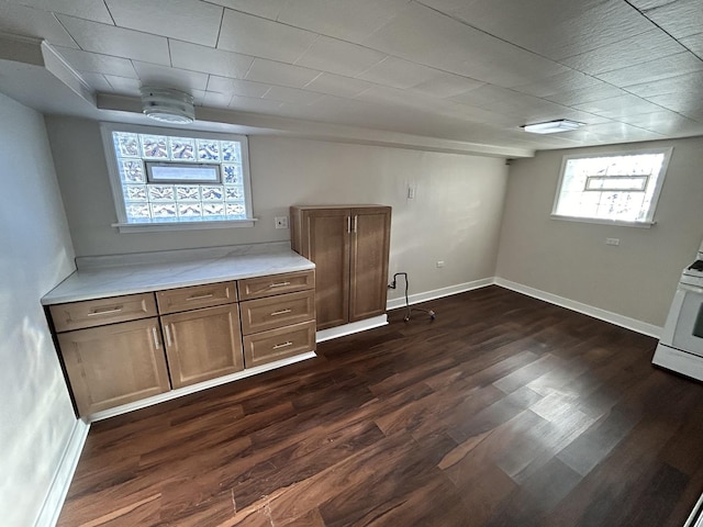 basement featuring baseboards and dark wood-type flooring