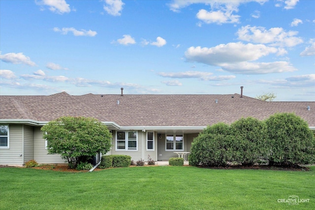 back of property with a yard and roof with shingles