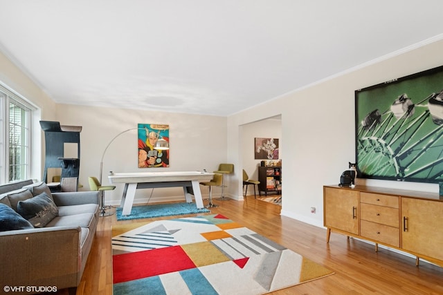 living area with baseboards, ornamental molding, and wood finished floors