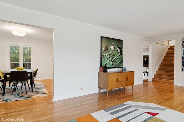 living area featuring stairway, baseboards, crown molding, and wood finished floors