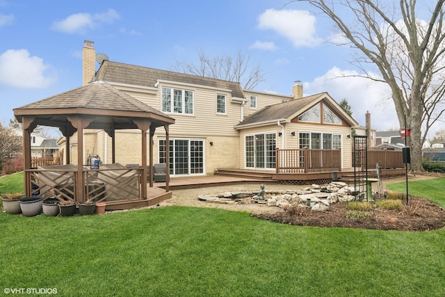 rear view of property with a chimney, a lawn, a wooden deck, a gazebo, and a shingled roof