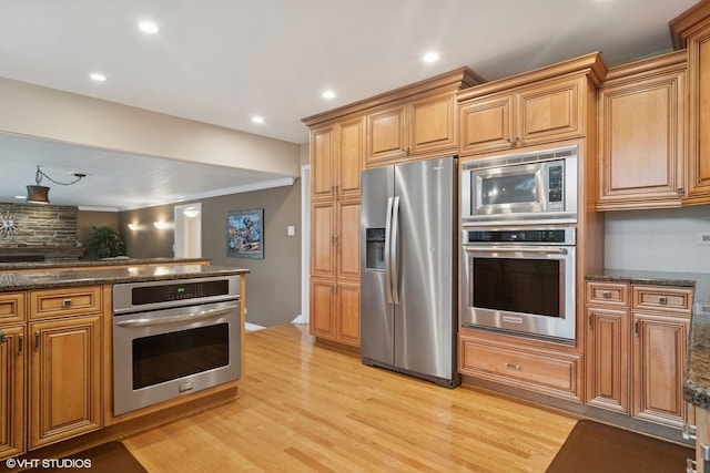 kitchen featuring stainless steel appliances, light wood-type flooring, and dark stone countertops