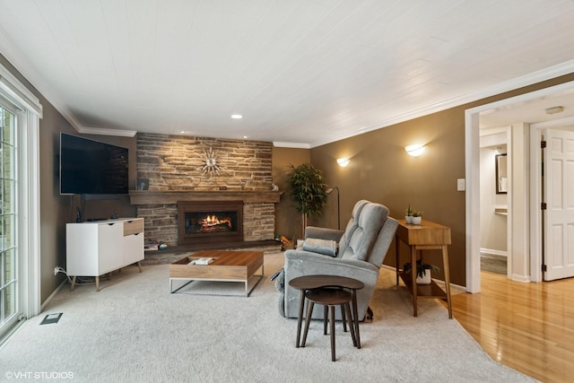living area with wood finished floors, a fireplace, ornamental molding, and visible vents