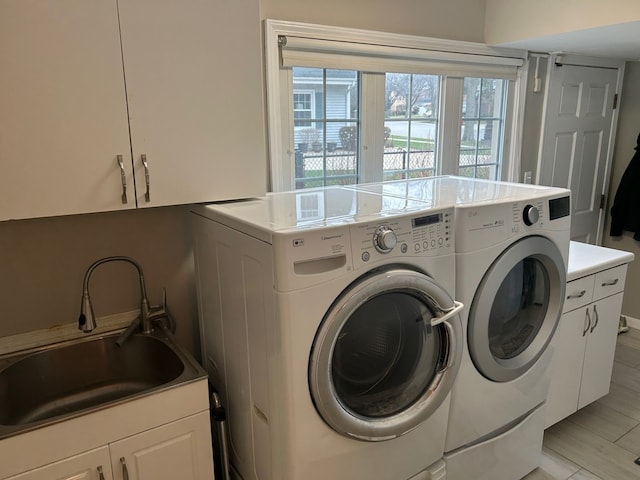 laundry room featuring independent washer and dryer, a sink, and cabinet space