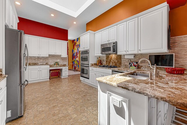 kitchen with appliances with stainless steel finishes, tasteful backsplash, vaulted ceiling, white cabinets, and a peninsula