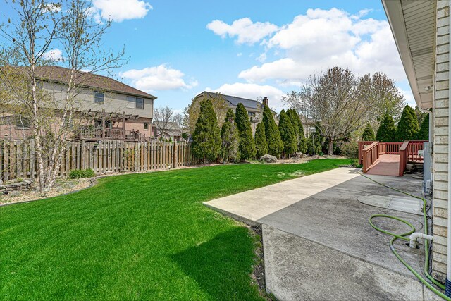 view of yard with fence, a wooden deck, and a patio area