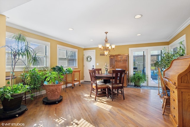 dining area with light wood-type flooring, an inviting chandelier, crown molding, and a healthy amount of sunlight