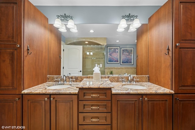 full bathroom featuring a sink, a shower stall, an inviting chandelier, and double vanity