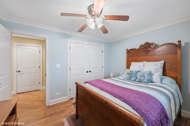 bedroom with a closet, baseboards, ornamental molding, ceiling fan, and light wood-style flooring