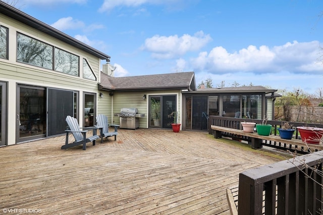 wooden deck with fence, a sunroom, and area for grilling