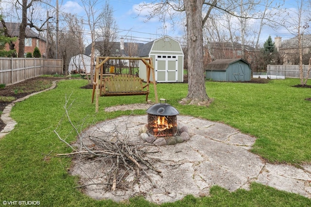 view of yard with a fenced backyard, an outdoor structure, a storage unit, a playground, and a fire pit
