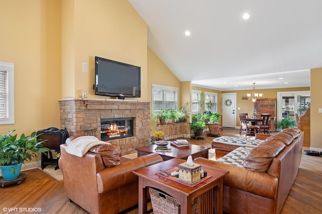 living room featuring a chandelier, a stone fireplace, baseboards, and wood finished floors