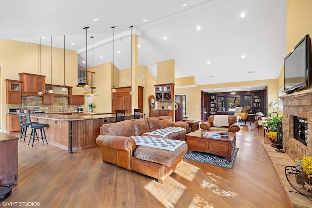 living area with high vaulted ceiling, a fireplace, beam ceiling, and wood finished floors