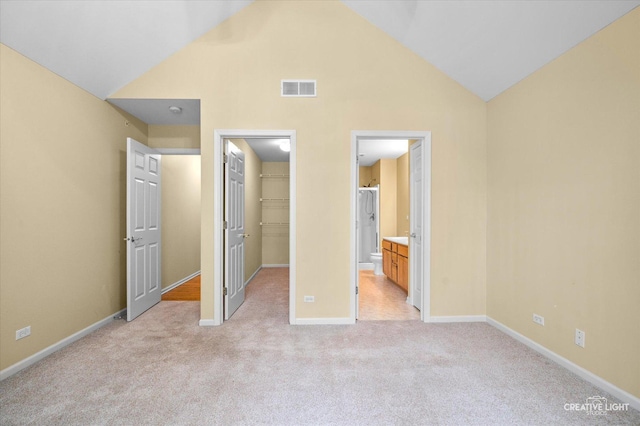 unfurnished bedroom with a closet, a spacious closet, visible vents, light carpet, and baseboards