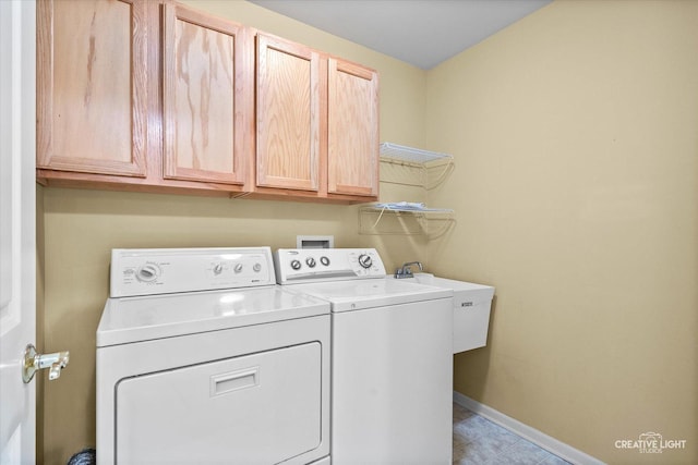 laundry room with cabinet space, washer and clothes dryer, baseboards, and a sink