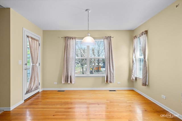 unfurnished dining area with light wood-style flooring, baseboards, and visible vents