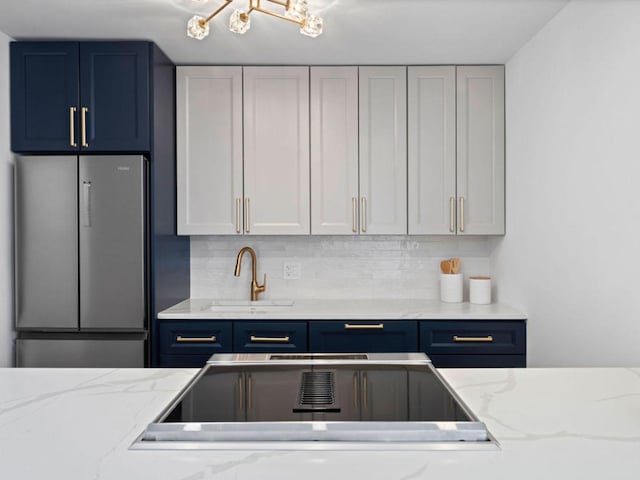 1355 N Sandburg Ter Unit 906D, Chicago, IL 60610 - kitchen featuring blue cabinets, stainless steel refrigerator, tasteful backsplash, and a sink
