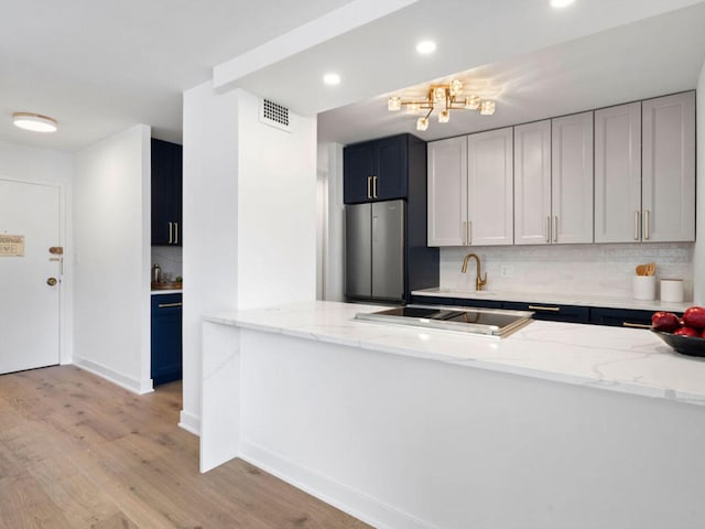 1355 N Sandburg Ter Unit 906D, Chicago, IL 60610 - kitchen featuring light stone countertops, tasteful backsplash, light wood-type flooring, and freestanding refrigerator