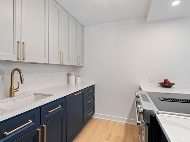 1355 N Sandburg Ter Unit 906D, Chicago, IL 60610 - kitchen with blue cabinets, a sink, light wood finished floors, white cabinets, and light stone countertops