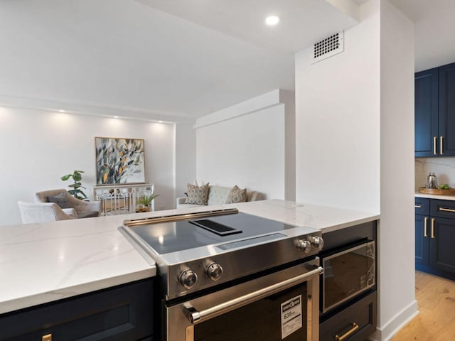 1355 N Sandburg Ter Unit 906D, Chicago, IL 60610 - kitchen featuring open floor plan, stainless steel electric range, light wood-type flooring, visible vents, and light stone countertops