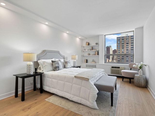 1355 N Sandburg Ter Unit 906D, Chicago, IL 60610 - bedroom featuring a city view, baseboards, light wood-type flooring, and a wall unit AC