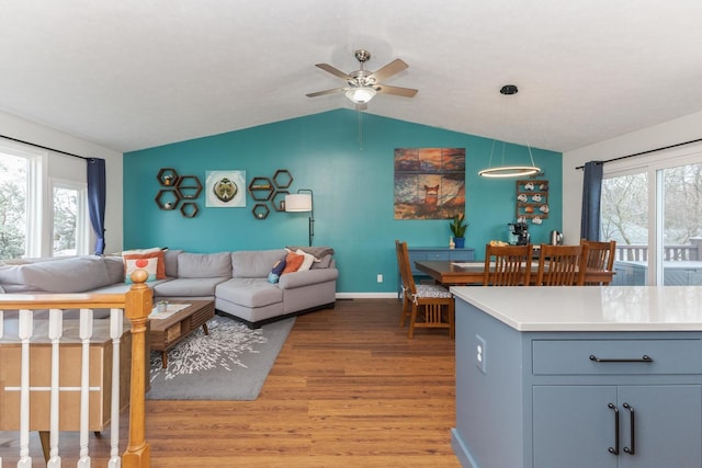 living room with a wealth of natural light, lofted ceiling, wood finished floors, and ceiling fan