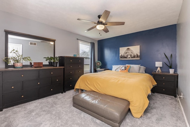 bedroom with visible vents, light colored carpet, baseboards, and ceiling fan