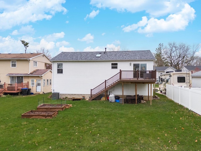 rear view of house with a yard, a garden, a deck, and fence