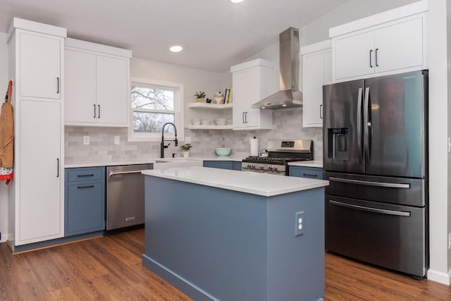 kitchen featuring light countertops, appliances with stainless steel finishes, wall chimney exhaust hood, and white cabinetry