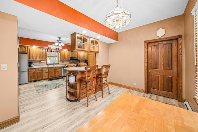 2513 Woods St, West Brooklyn, IL 61378 - kitchen with stainless steel appliances, under cabinet range hood, baseboards, a sink, and brown cabinetry