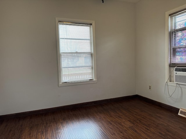 empty room featuring baseboards, visible vents, and dark wood-type flooring
