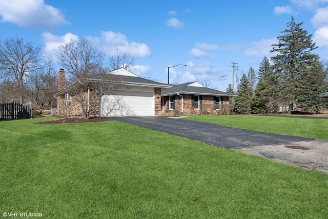 ranch-style house featuring a chimney, a front yard, aphalt driveway, and an attached garage